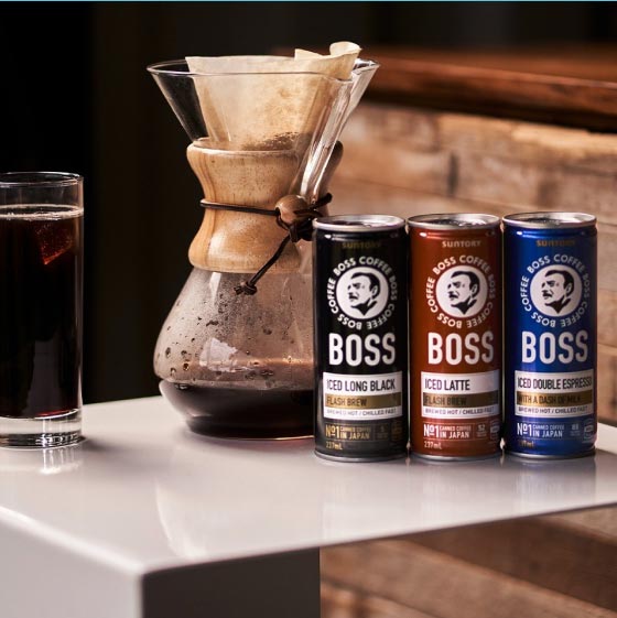 Three cans of Boss coffee next to a coffee paper filter