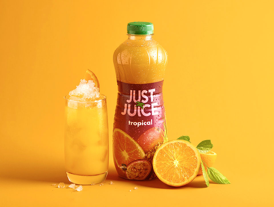 A glass and bottle of Just Juice on an orange background