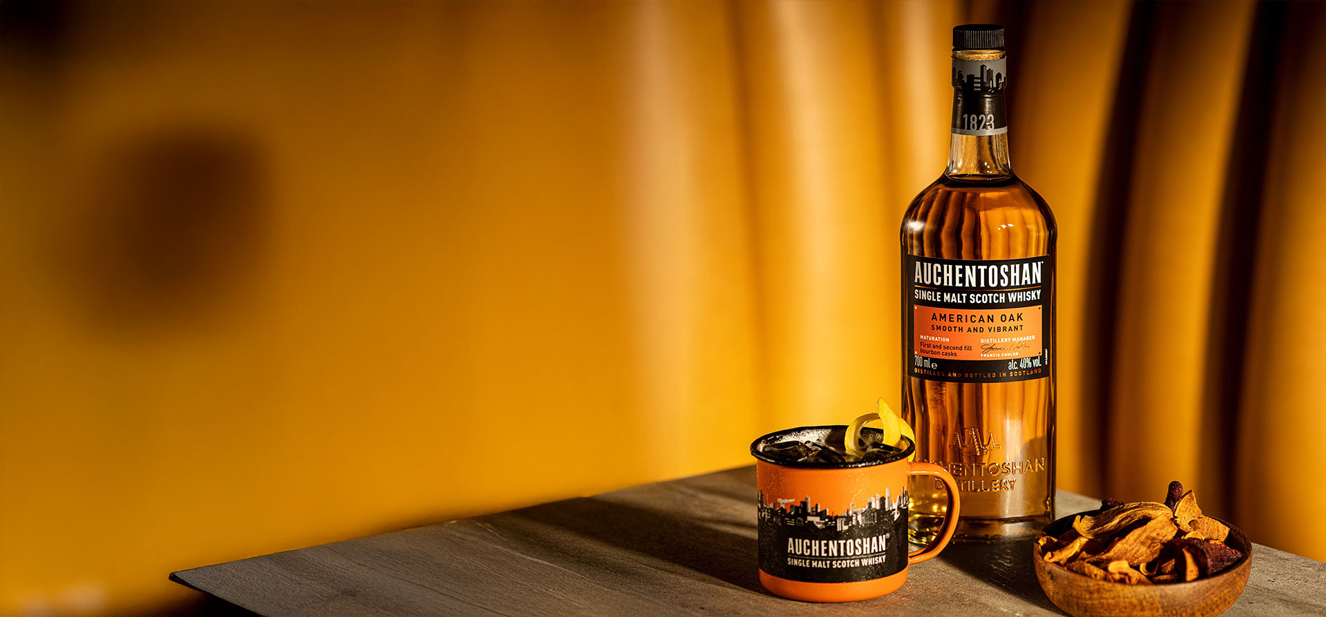 A bottle and cup of Auchentoshan on a wooden table