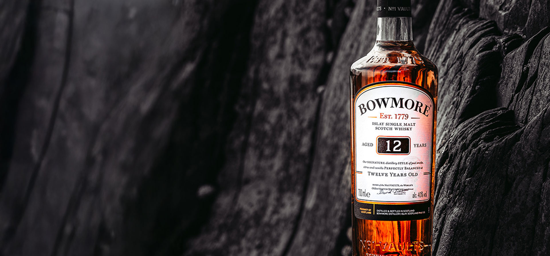 A bottle of Bowmore whisky against a dark wooden background