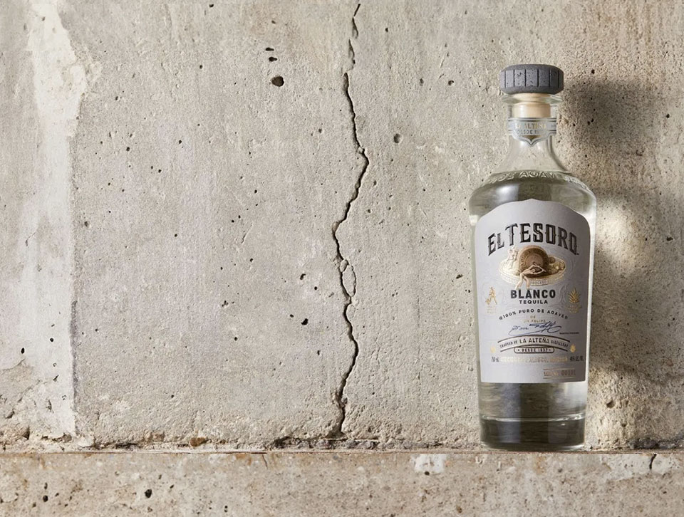 A bottle of El Tesoro placed against an off-white concrete background