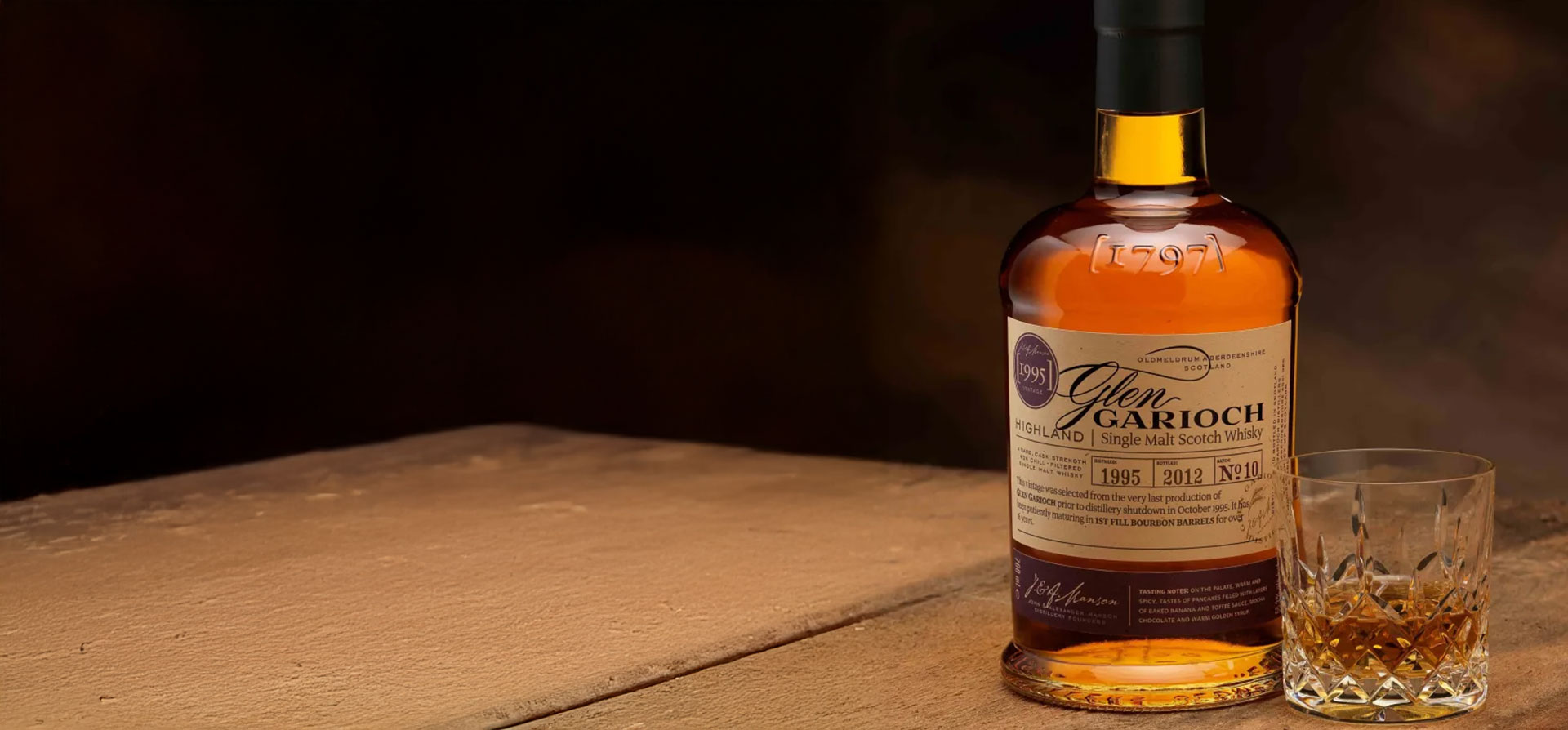 A bottle and glass of neat Glen Garioch Whiskey on a wooden barrel 