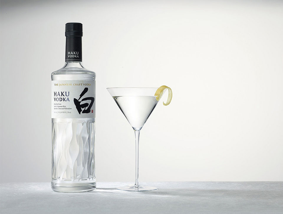 A bottle of Haku vodka and a clear cocktail against a white background