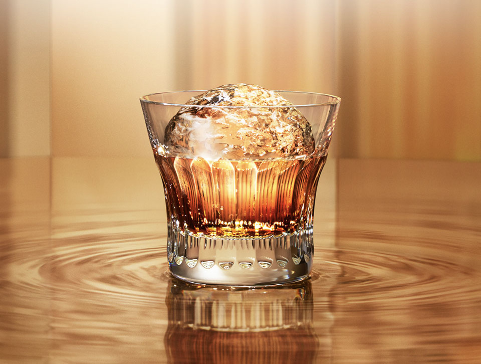 A glass of whisky on the rocks against a gold background