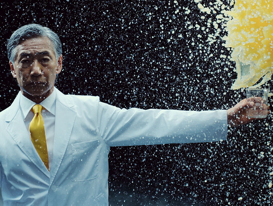 Man holding an empty glass and lemon juice splashing above