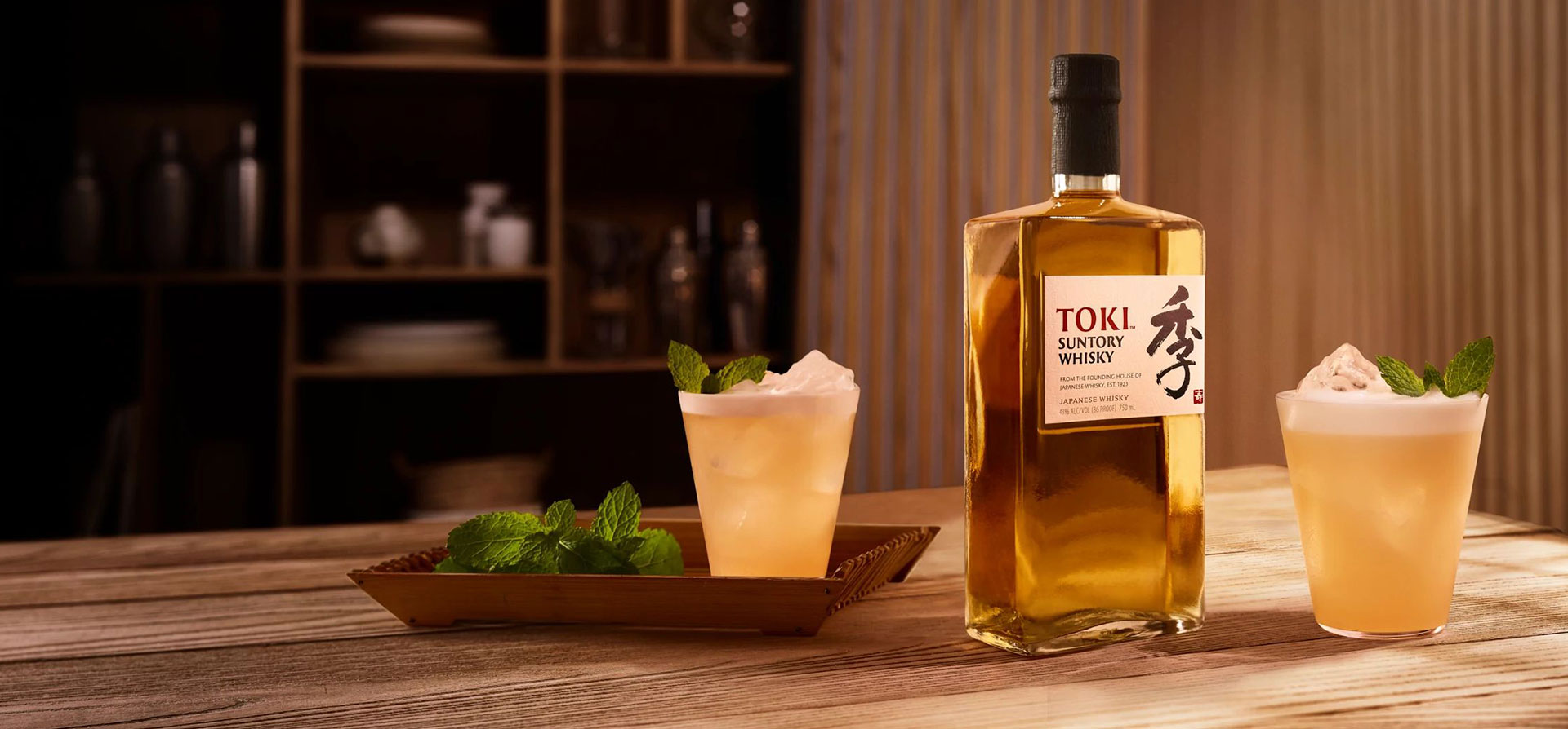 A bottle of Toki and cocktails on a wooden table