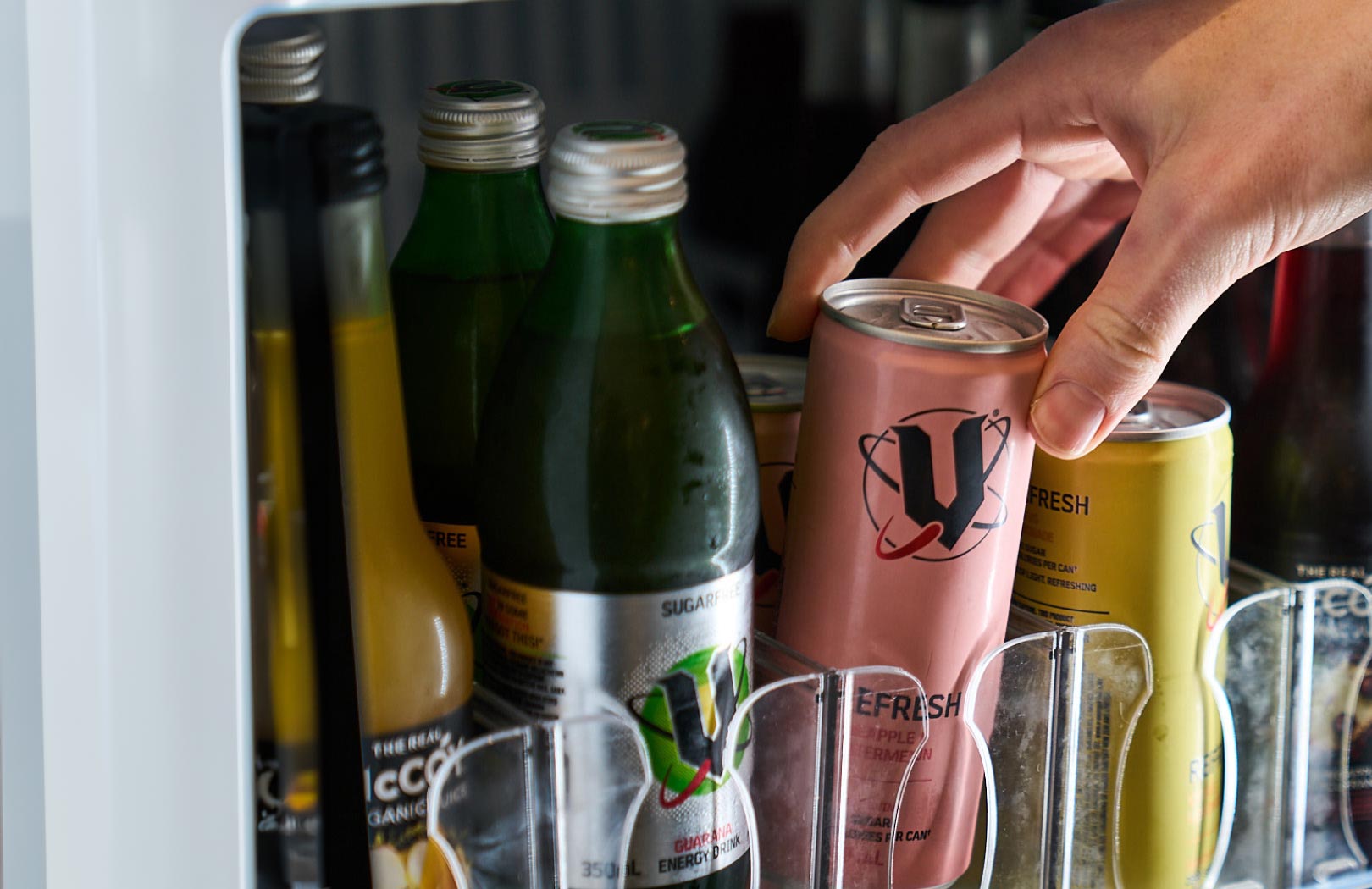 Close up of hand reaching out for a can of V Energy in the fridge