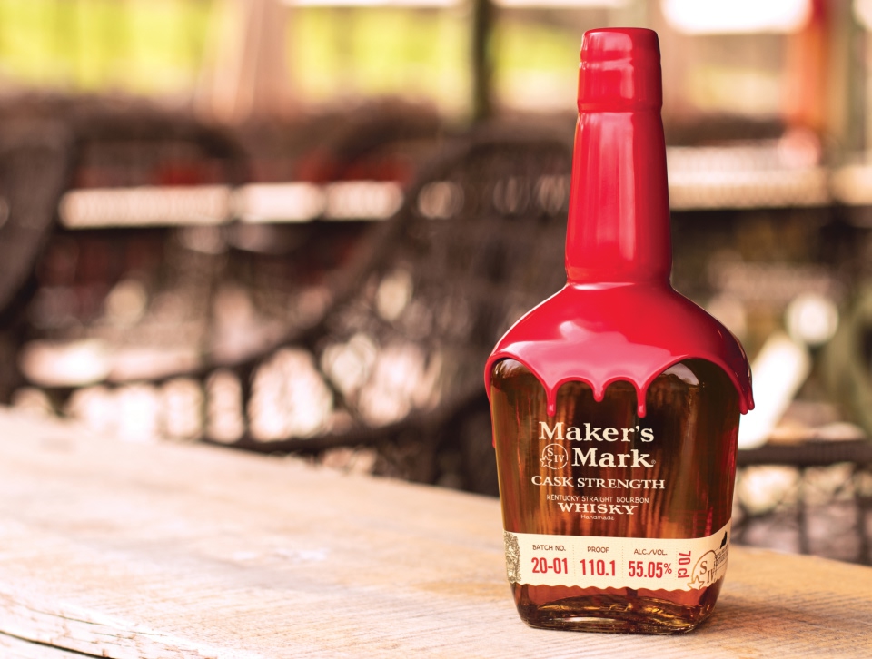 A bottle of Maker's Mark on a wooden table in an outdoor scene