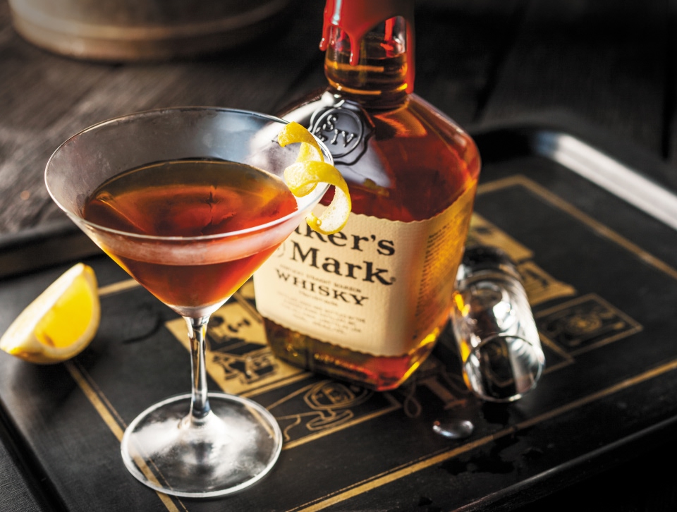 A bottle of Maker's Mark and a cocktail glass on a black tray