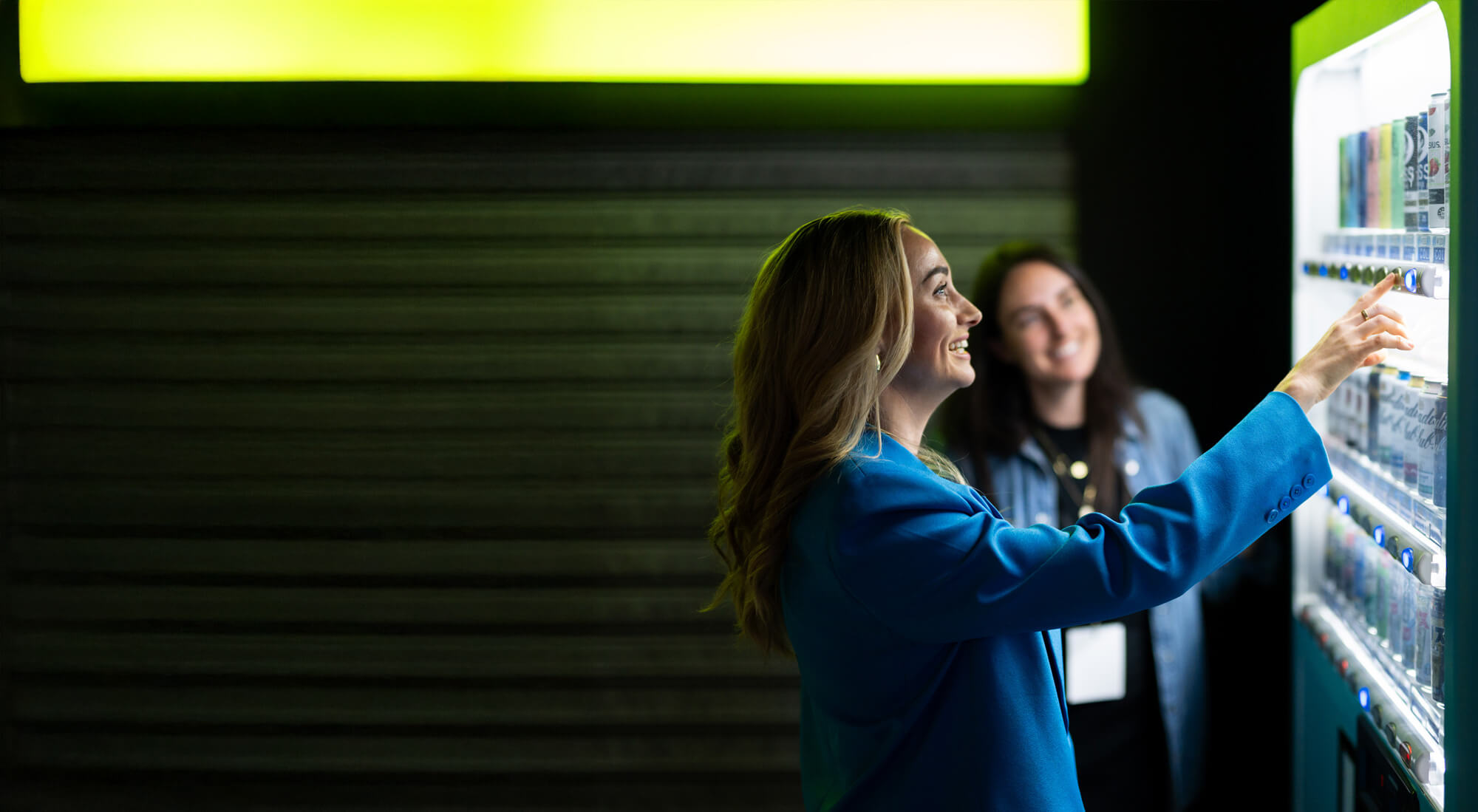 A smiling woman pressing a button on a vending machine