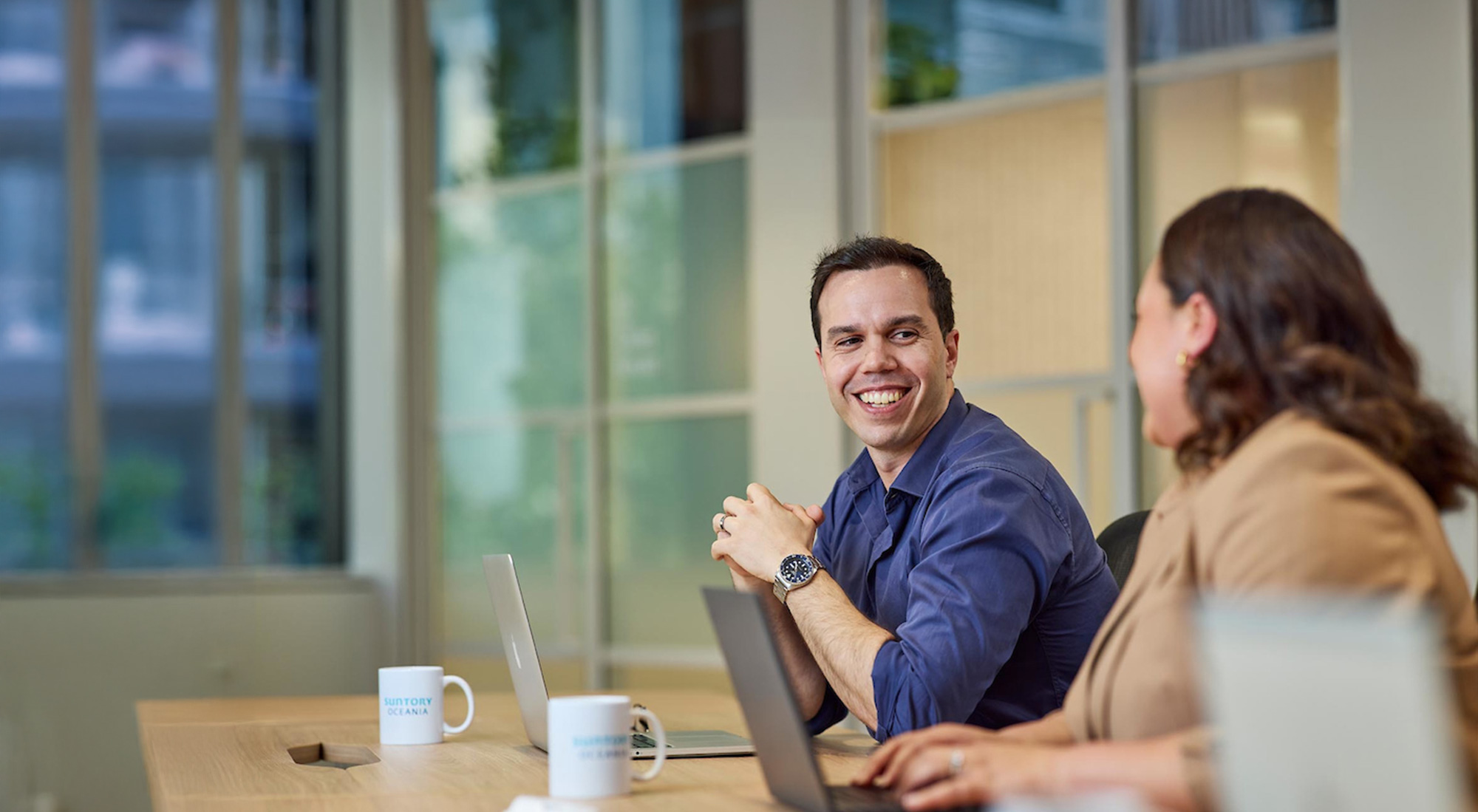 Two people talking and smiling in an office.