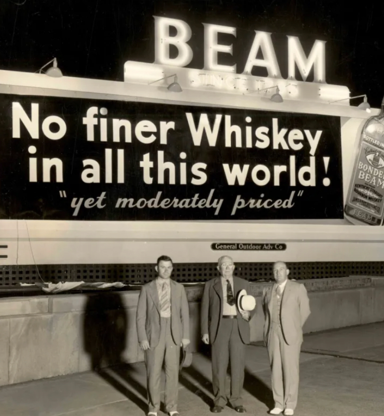 Three smartly dressed men stand before a Jim Beam billboard from the 1950s.