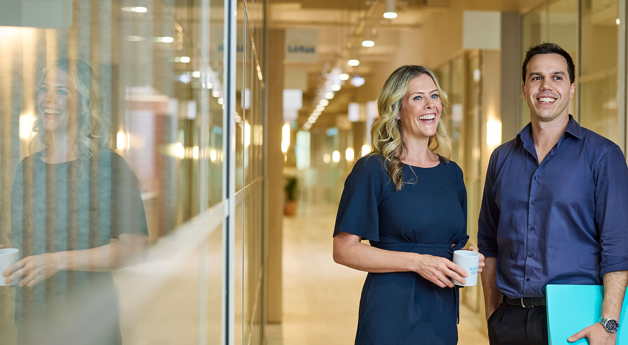 2 people in navy shirts standing in an office space